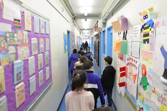 Students walk in a school hallway.